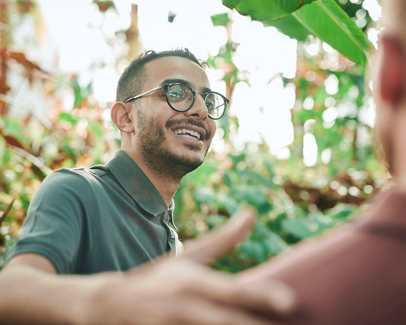 A man smiles as he greets a friend.