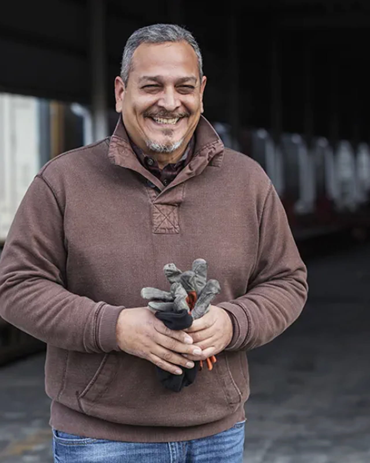  A man smiles as he holds his work gloves in a subway station.