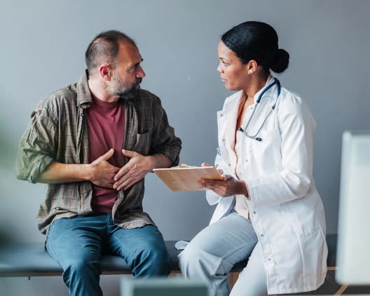 A patient points to his stomach as he consults with his doctor.
