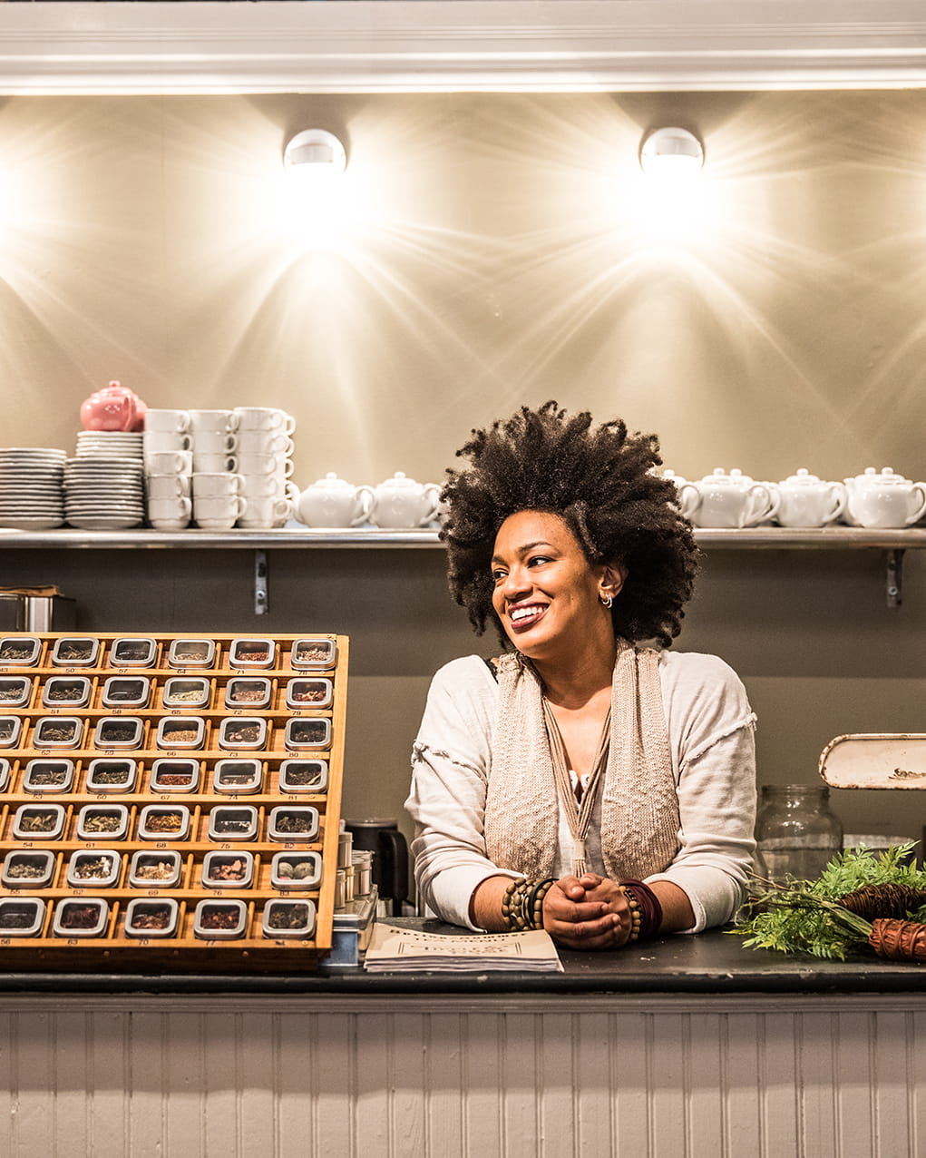 A smiling woman standing behind the counter at a tea shop.
