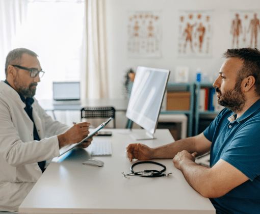 Un hombre consulta con un doctor mientras están sentados en un escritorio.