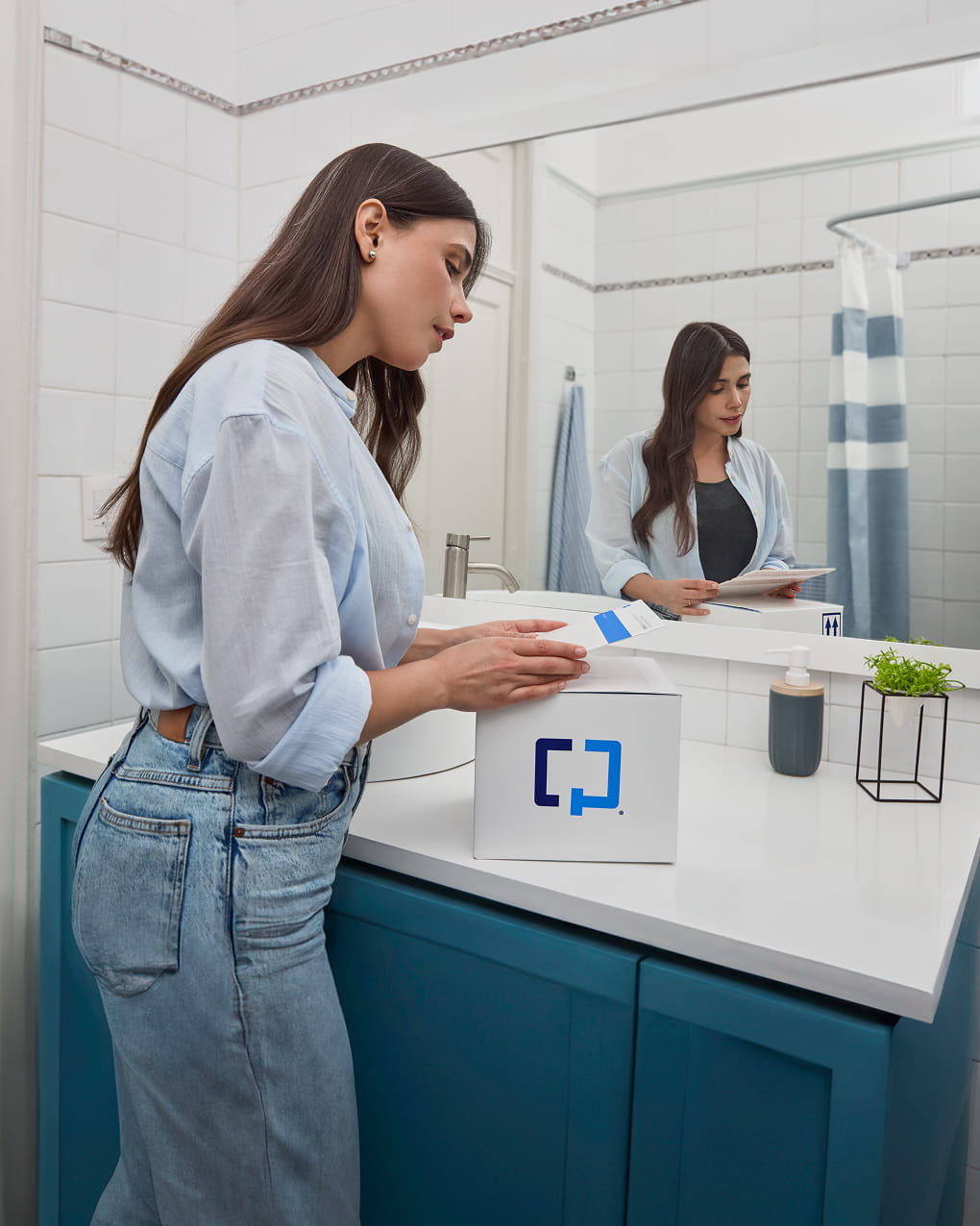 Una mujer se prepara para usar una caja Cologuard Plus en el baño.